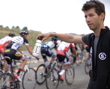 Team helper handing drinks to cyclists