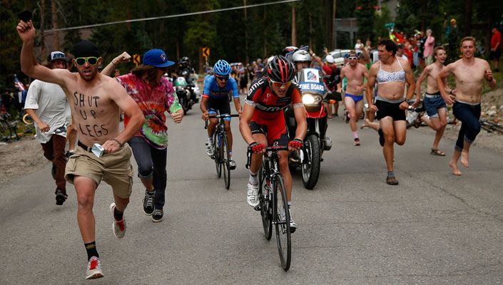 fans running aside cyclists up a climb