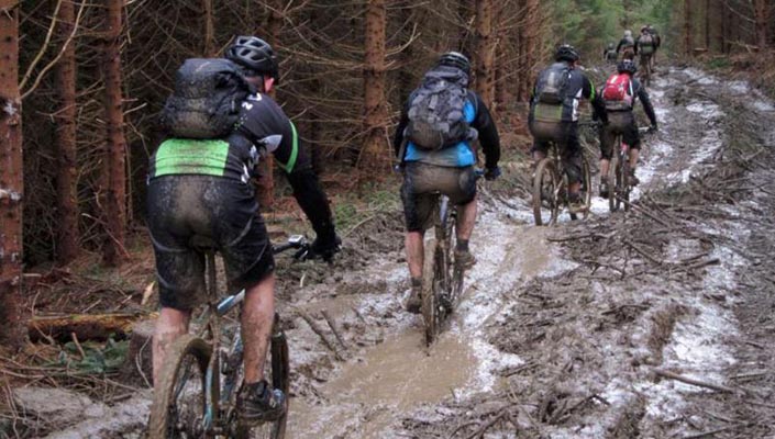 mountain bikers in mud wearing hydration packs