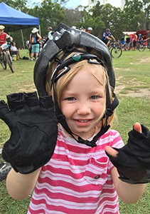 Kid with bike helmet on backwards and gloves that are too big